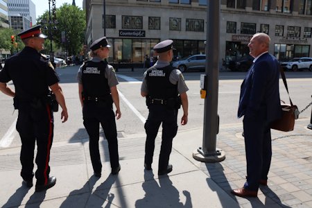 Officers and a member of the public on a street corner in the downtown area
