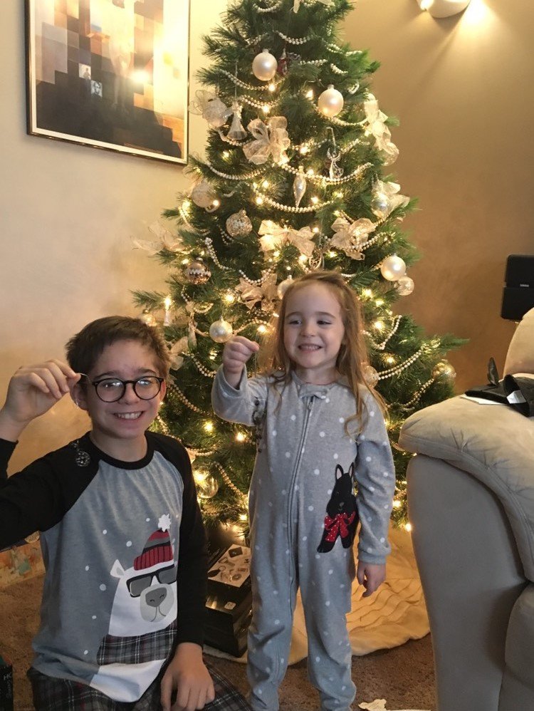 Kandice's children, Nethan and Kaestin, holding ornaments in front of a Christmas tree.